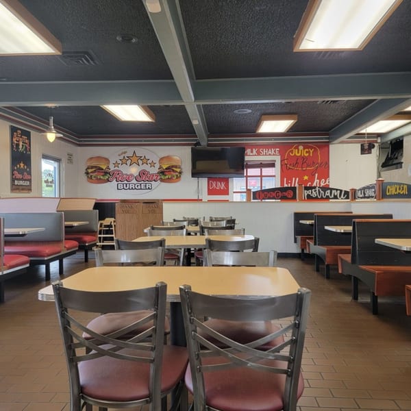 Interior of Five Star Burger restaurant with empty tables, booths, and a large burger mural.